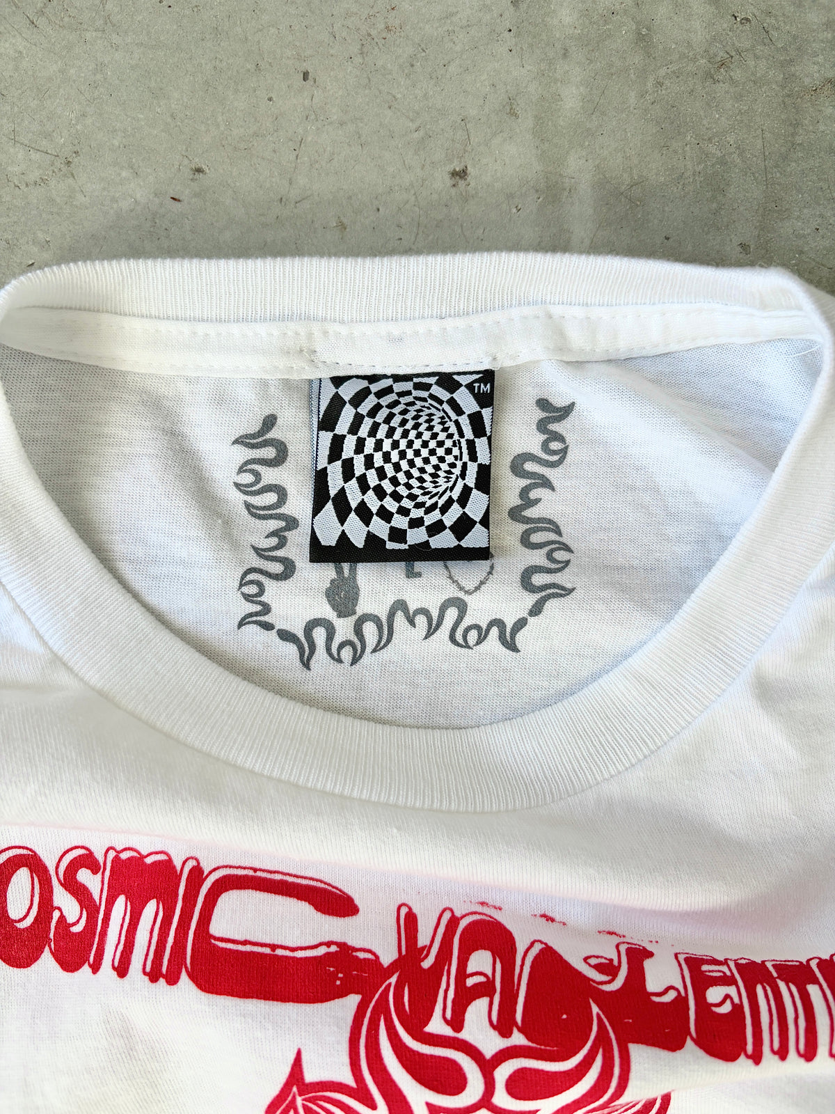 Close-up of the ribbed collar with a black and white checkered spiral woven tag and hand-drawn text in gray ink