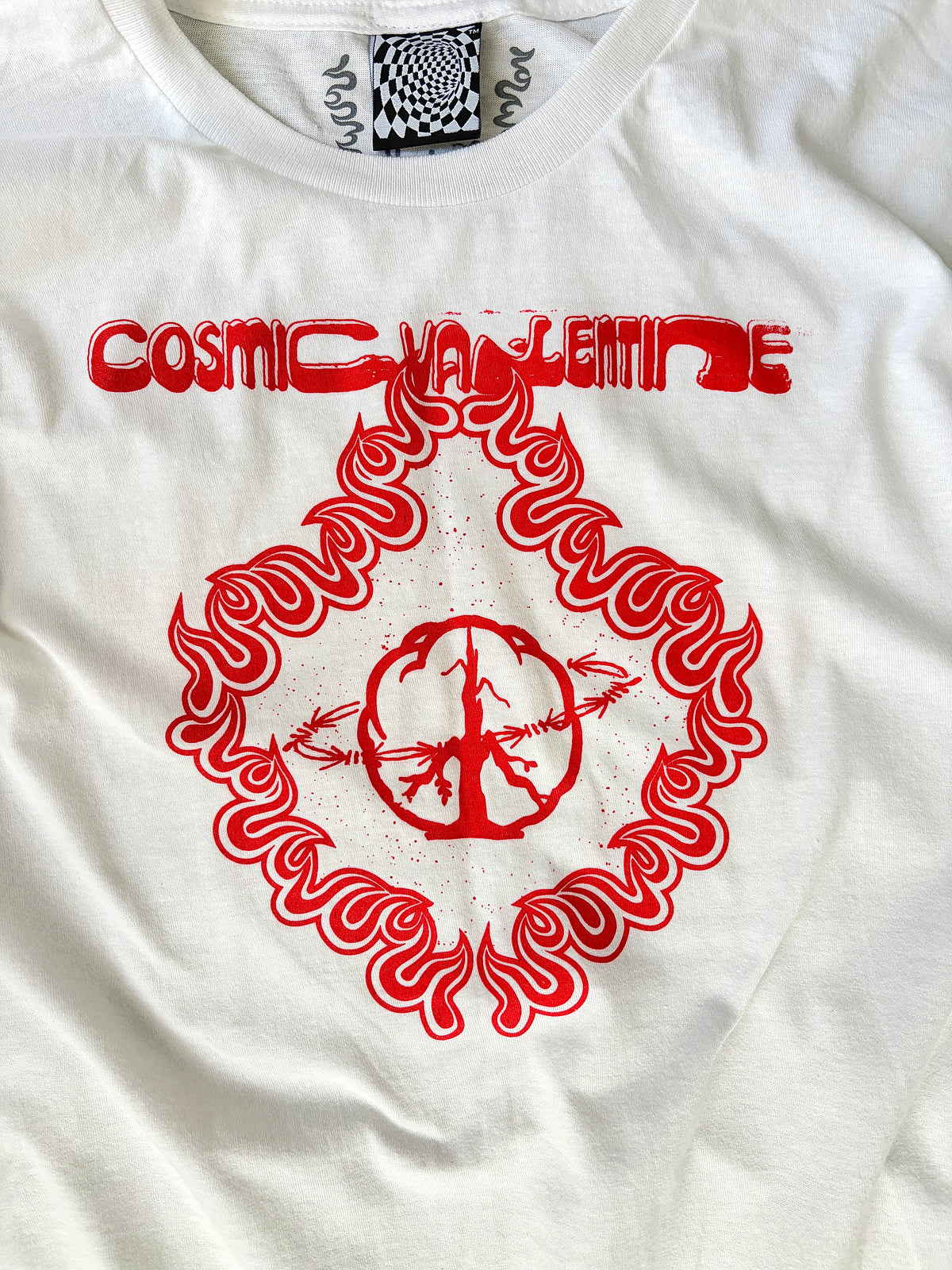Close-up of the red Cosmic Valentine wordmark and peace sign flame graphic printed on the chest