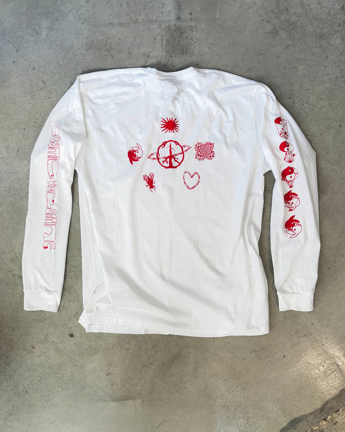 Back of white long sleeve t-shirt laid flat, red sun and peace sign design with a barbed wire heart, fly, and rabbit icon