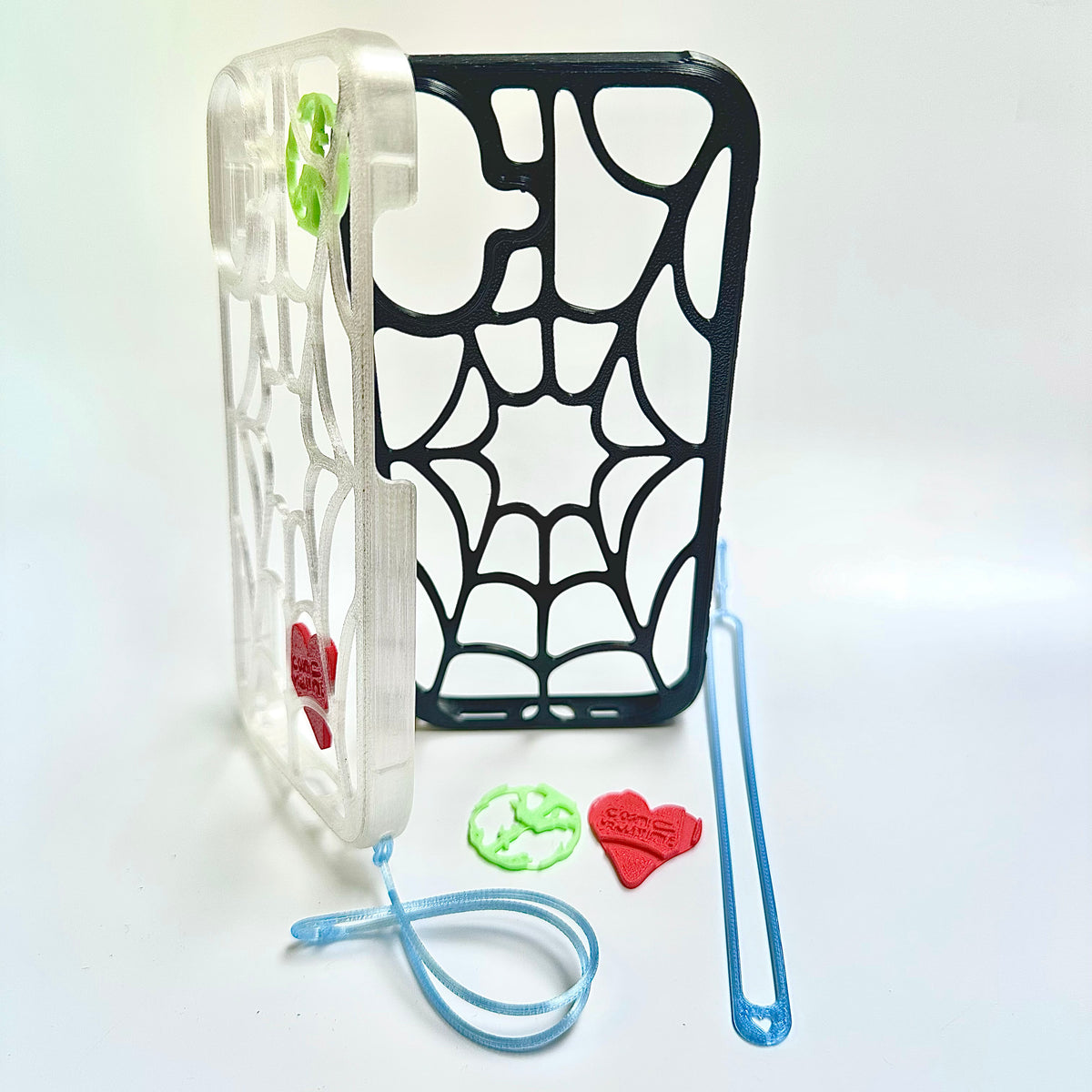 Clear and black spiderweb iPhone cases displayed with a blue wrist tether, red heart and green peace piece