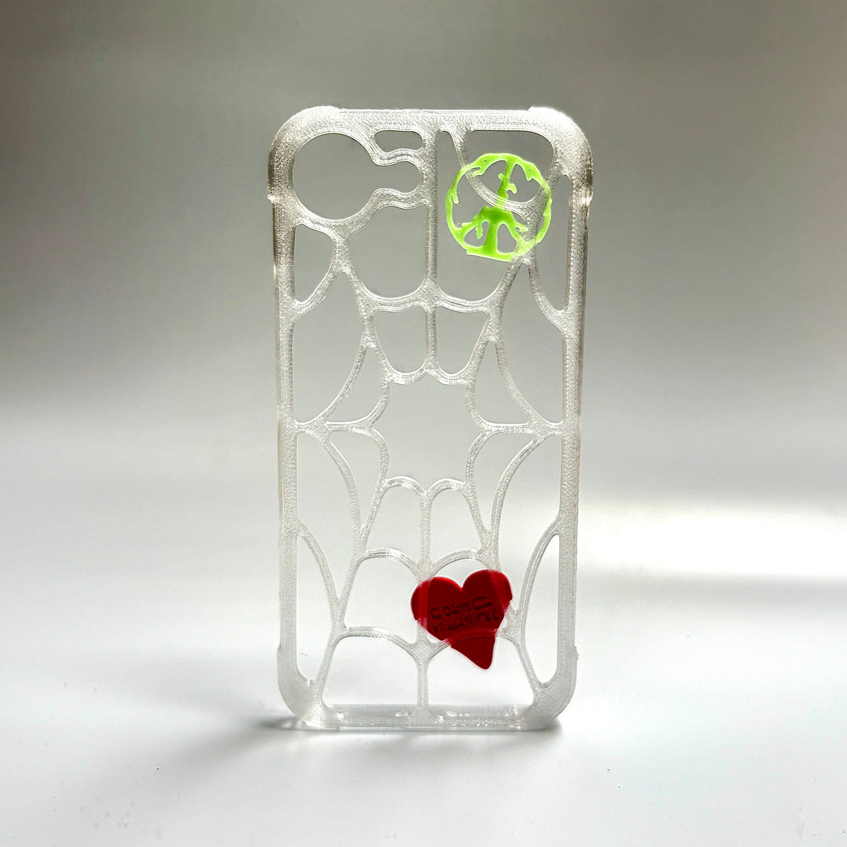 Clear spiderweb iPhone case with a green glow-in-the-dark peace piece and a red heart