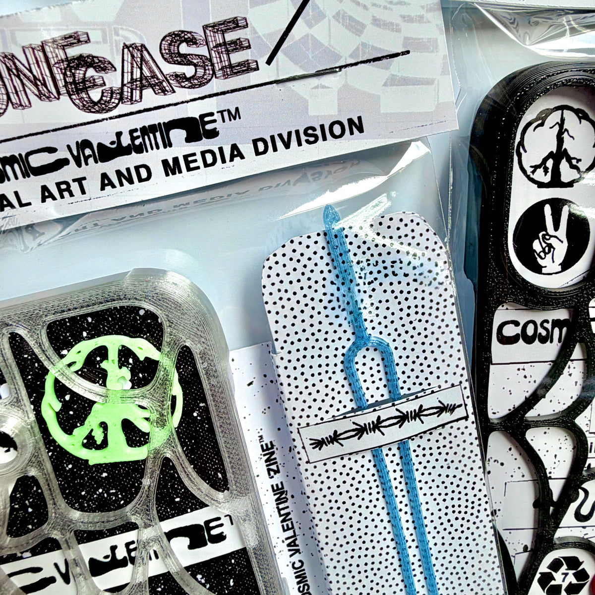 Close-up of hang-tag packaging with a green peace piece, blue tether and clear spiderweb case