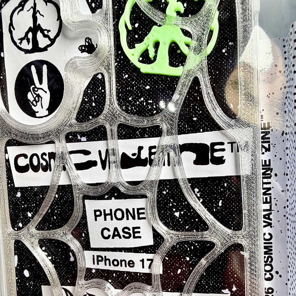 Close-up of a clear spiderweb case in packaging labeled PHONE CASE iPhone 17, with a green peace piece
