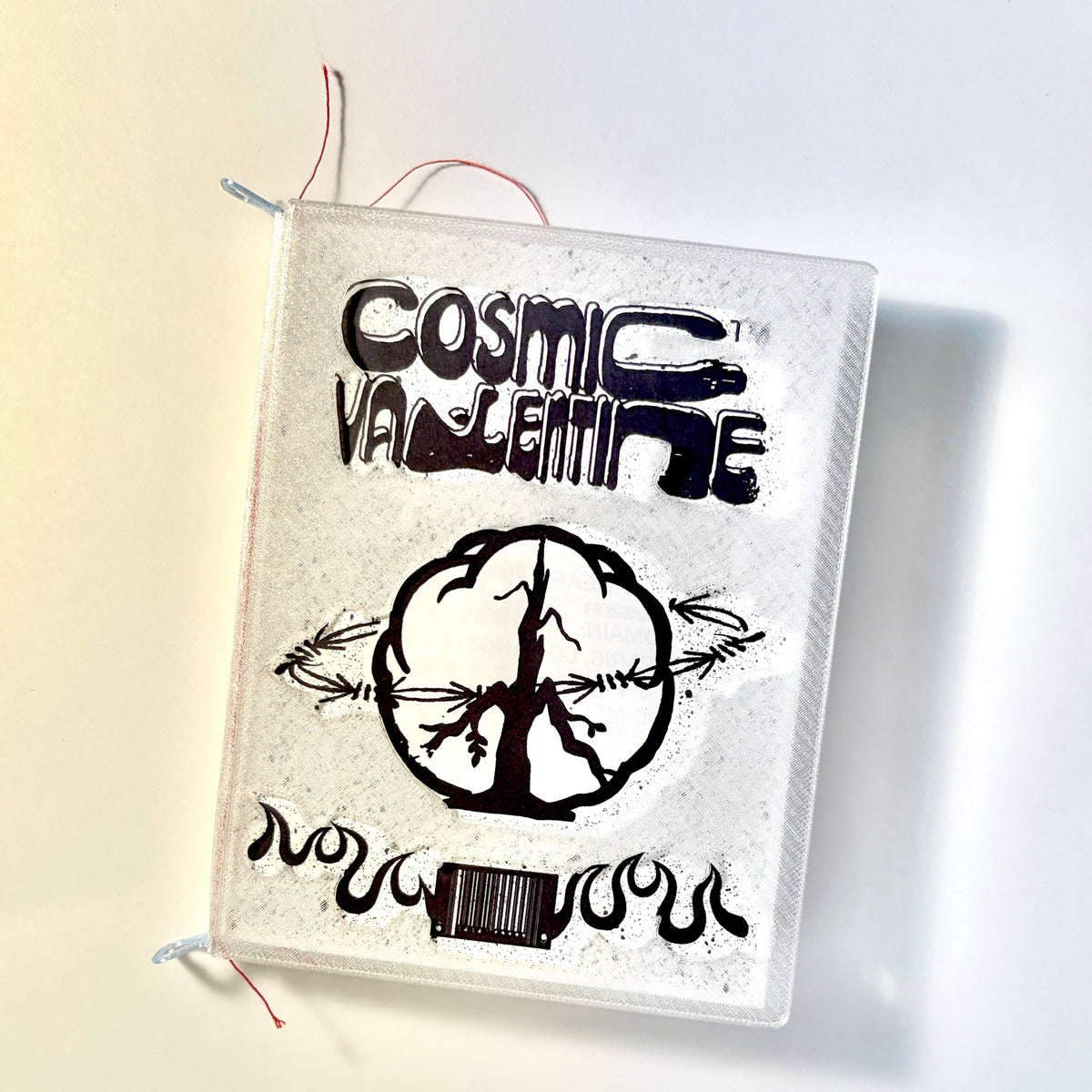 Cosmic Valentine Issue 1 zine with a clear textured cover, black wordmark and peace-sign art, and red thread binding